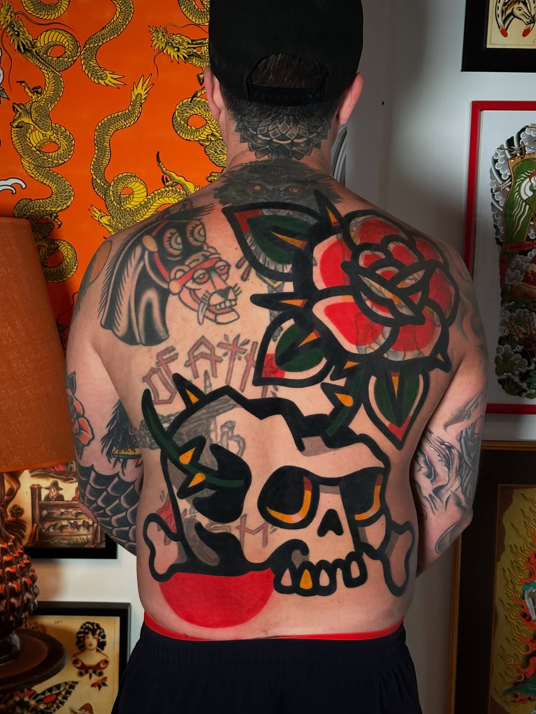 Full back piece featuring bold skull with roses, demons, and Asian-inspired elements in classic traditional style.