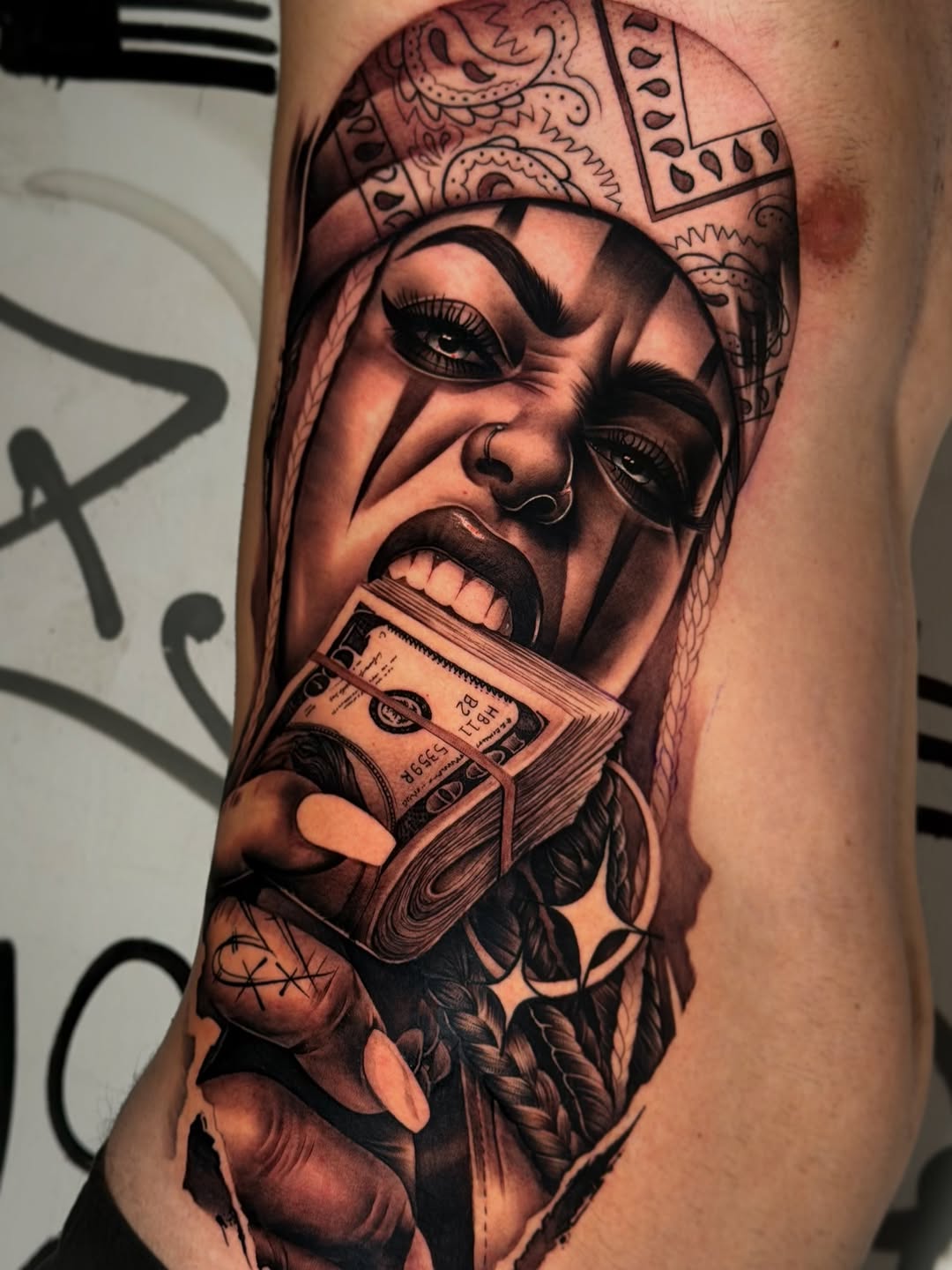 Woman's face wearing ornate headpiece holding fanned cash, rendered in black and grey with smooth shading on upper arm.