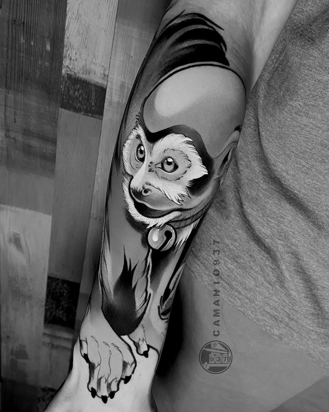 Black and grey lemur tattoo on forearm with detailed facial features, large expressive eyes, and decorative collar element.