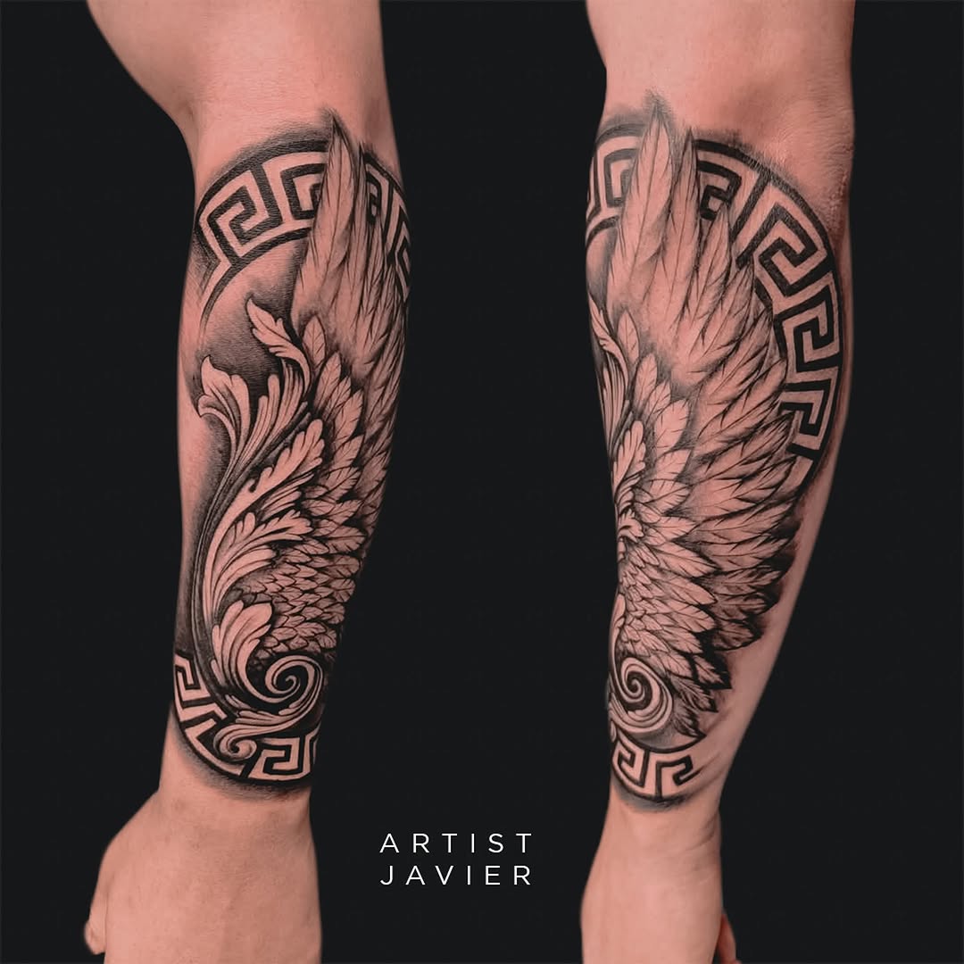 Matching black and grey wing tattoos on both calves with ornate Greek key patterns and detailed feather shading.