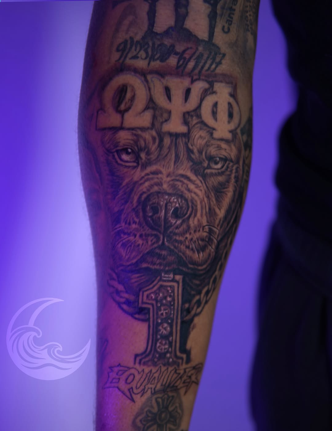 Black and grey bearded man's face with Greek letters and numerals on forearm under purple lighting.