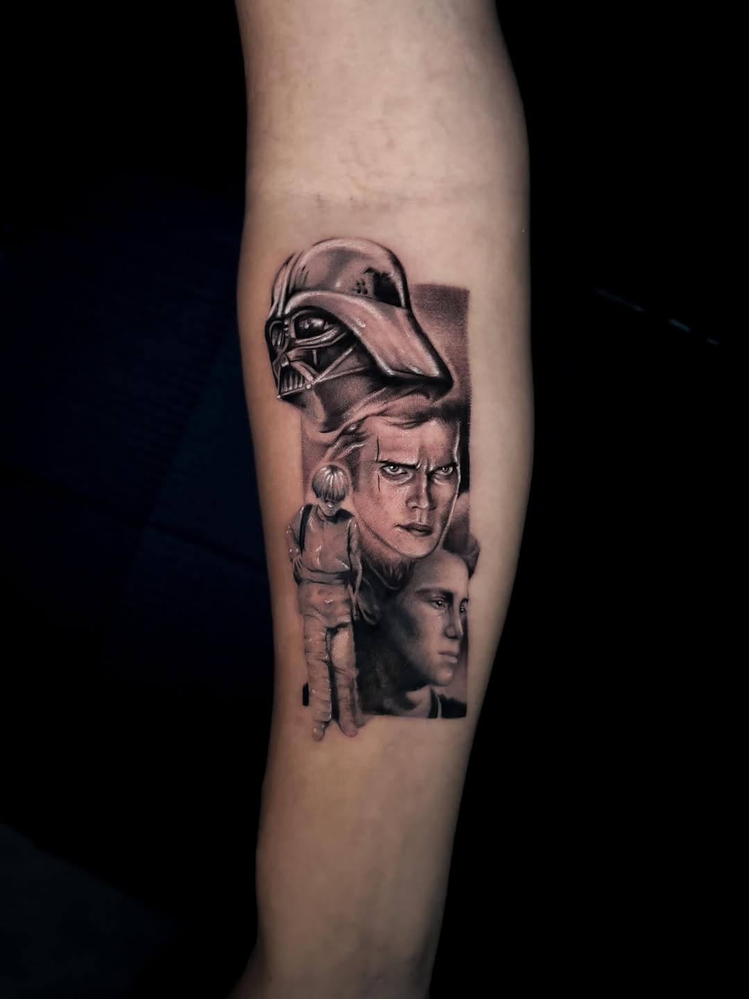Black and grey portrait tattoo on forearm featuring Darth Vader helmet above two male faces with detailed shading and smooth gradients.