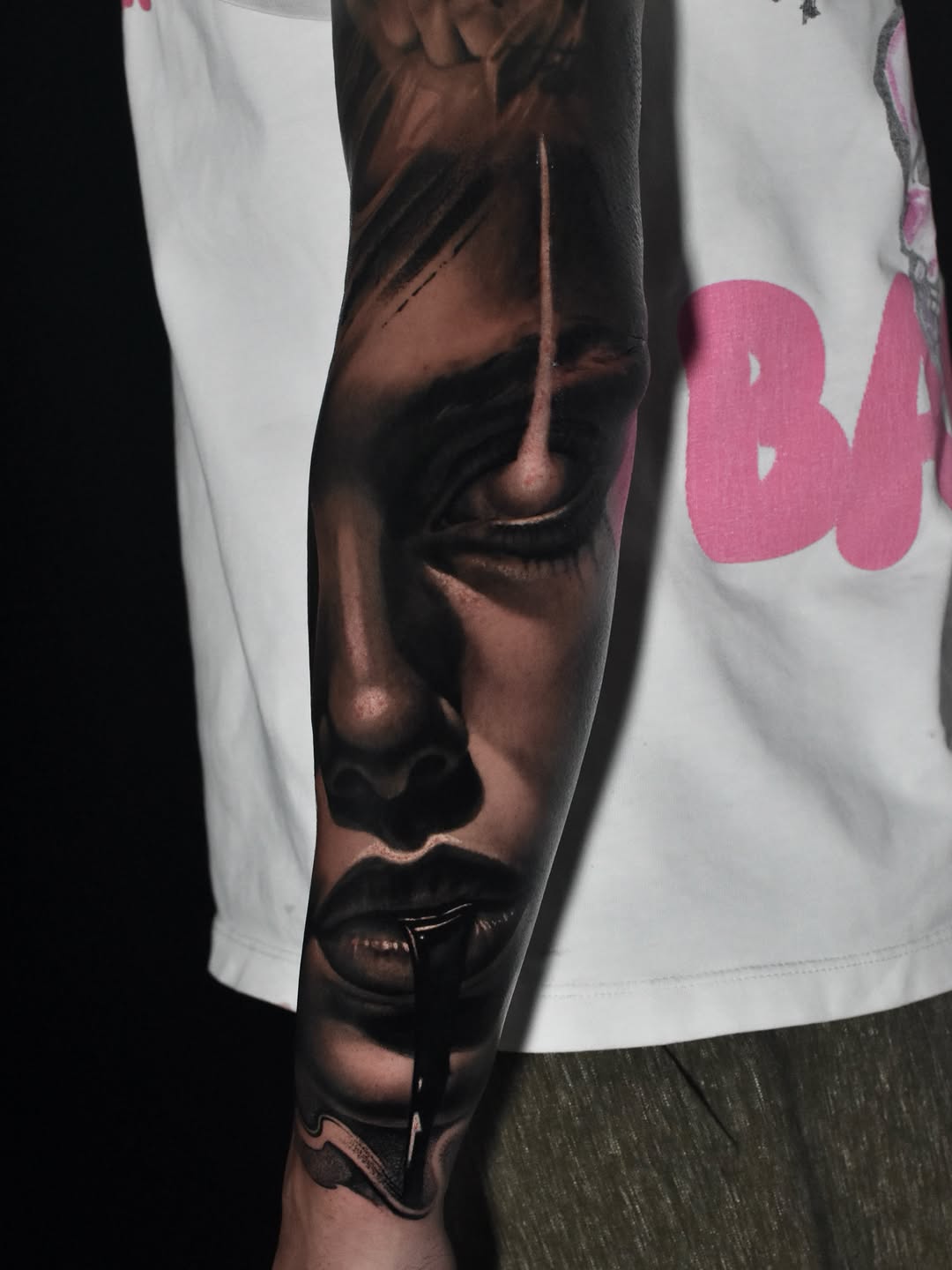 Black and grey portrait tattoo on forearm showing a face with dramatic shading and smooth gradients, displayed on skin.