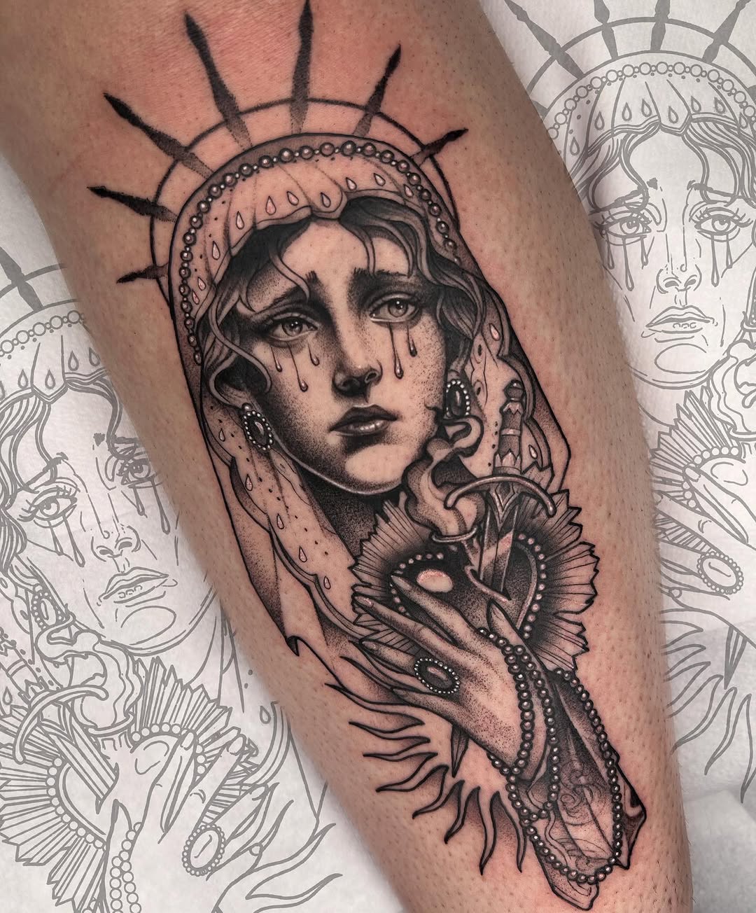 Black and grey portrait tattoo of a woman with halo and spikes, tears on her face, holding ornate dagger on upper arm.