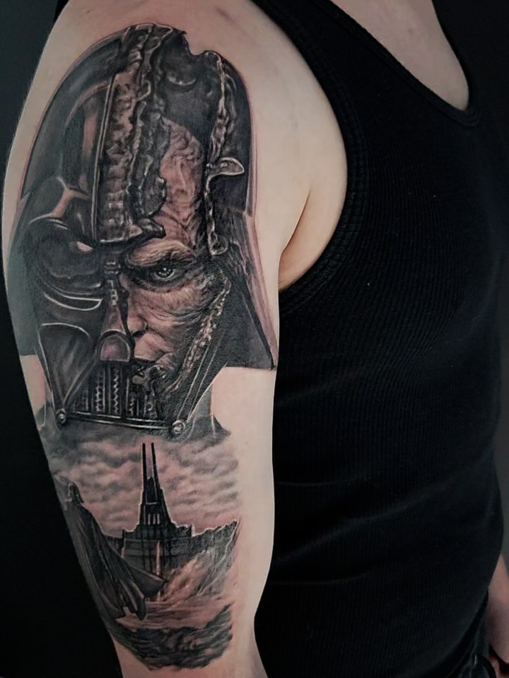 Upper arm tattoo featuring a split portrait with mechanical and human elements above a spacecraft, rendered in black and grey with smooth shading.