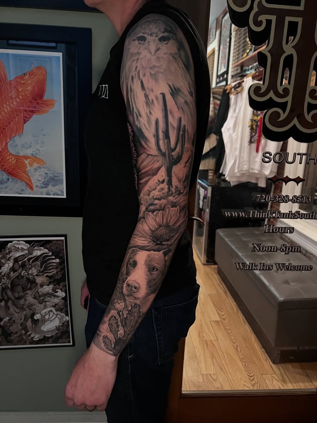 Full sleeve tattoo featuring an owl perched above a sunflower and dog portrait, rendered in black and grey with soft shading on the upper arm.
