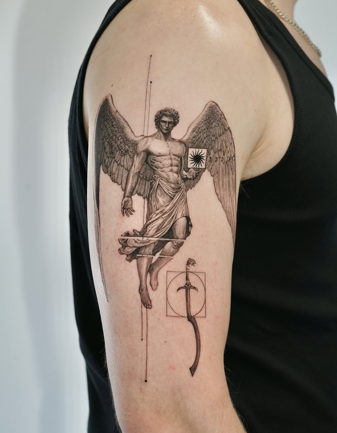 Winged angel figure with muscular torso holding a sword and shield with geometric elements on upper arm.