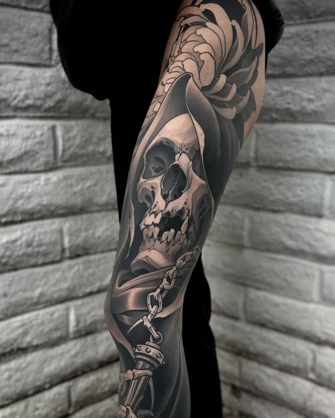 Full leg sleeve featuring a skull with flowing fabric, ornate dagger, and decorative floral elements in black and grey shading.