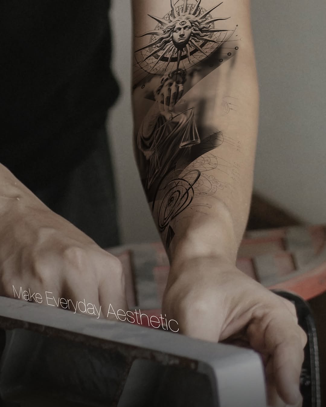 Black and grey tattoo on calf featuring a sun-faced figure with radiating spikes, draped fabric, and ornamental elements below in soft shading.