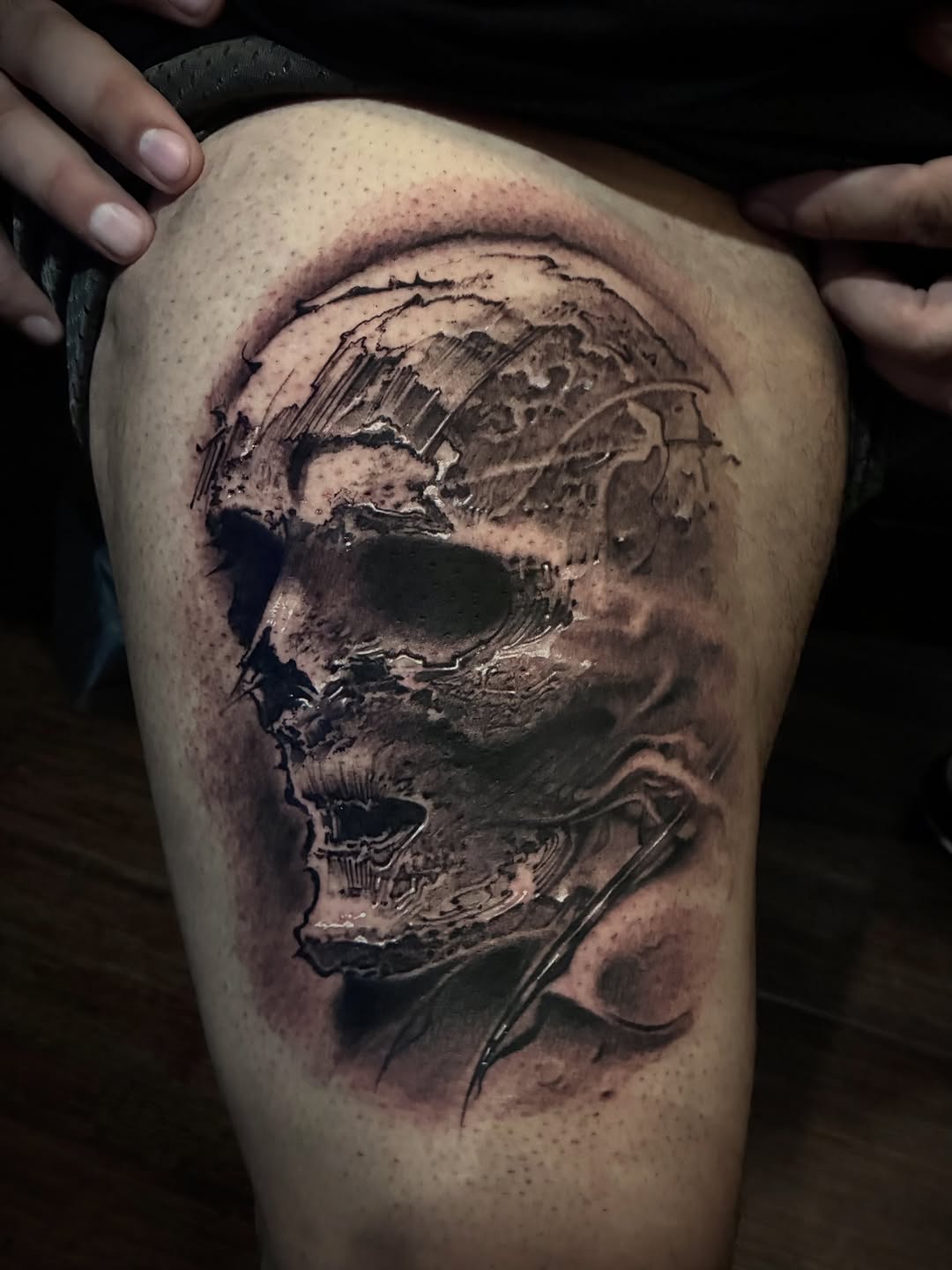 Detailed skull with anatomical shading and crosshatching on thigh, rendered in black and grey with dimensional depth.