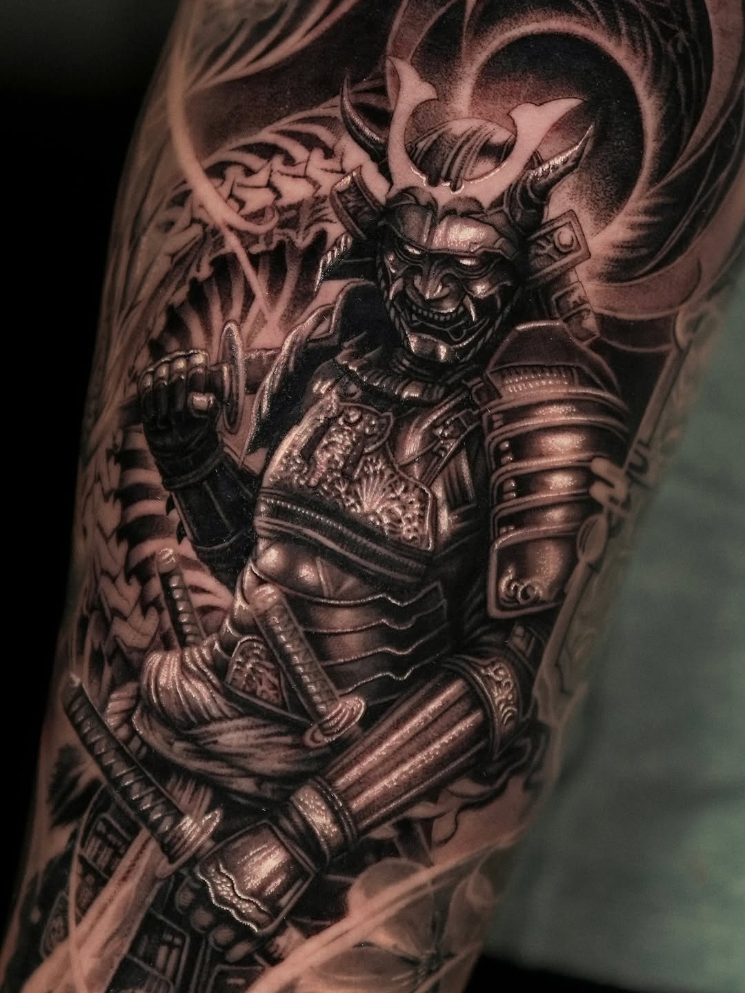 Ornate demon warrior with elaborate armor and horns in black and grey shading on upper arm, demonstrating detailed realism.