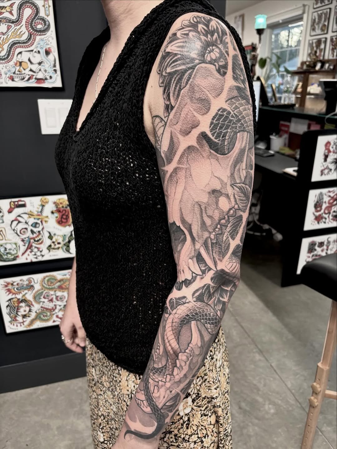 Full sleeve tattoo featuring a skull with floral elements and a koi fish, rendered in black and grey with smooth shading gradients.
