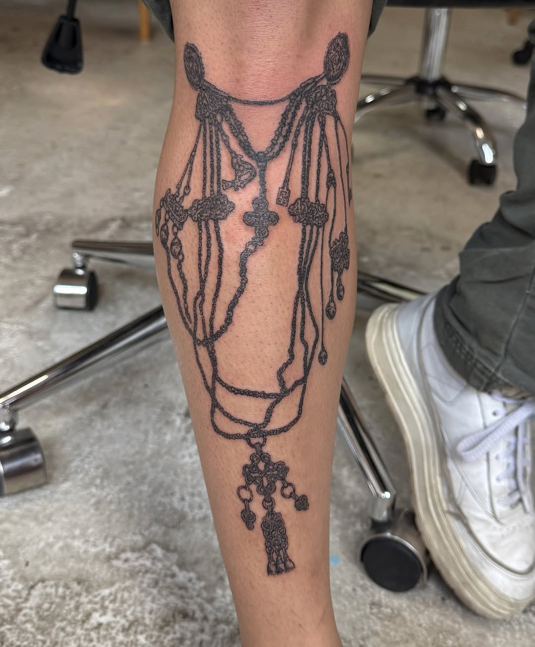 Ornamental horse head with draped tassels and hanging ornaments on the calf, intricate linework design.