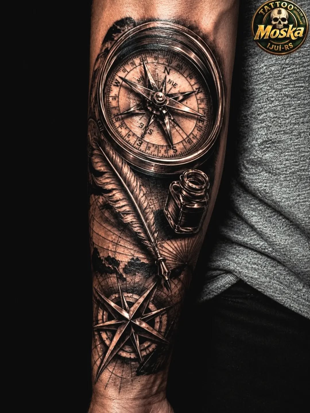 Monochromatic compass rose and nautical compass with feather and ink bottle on forearm.
