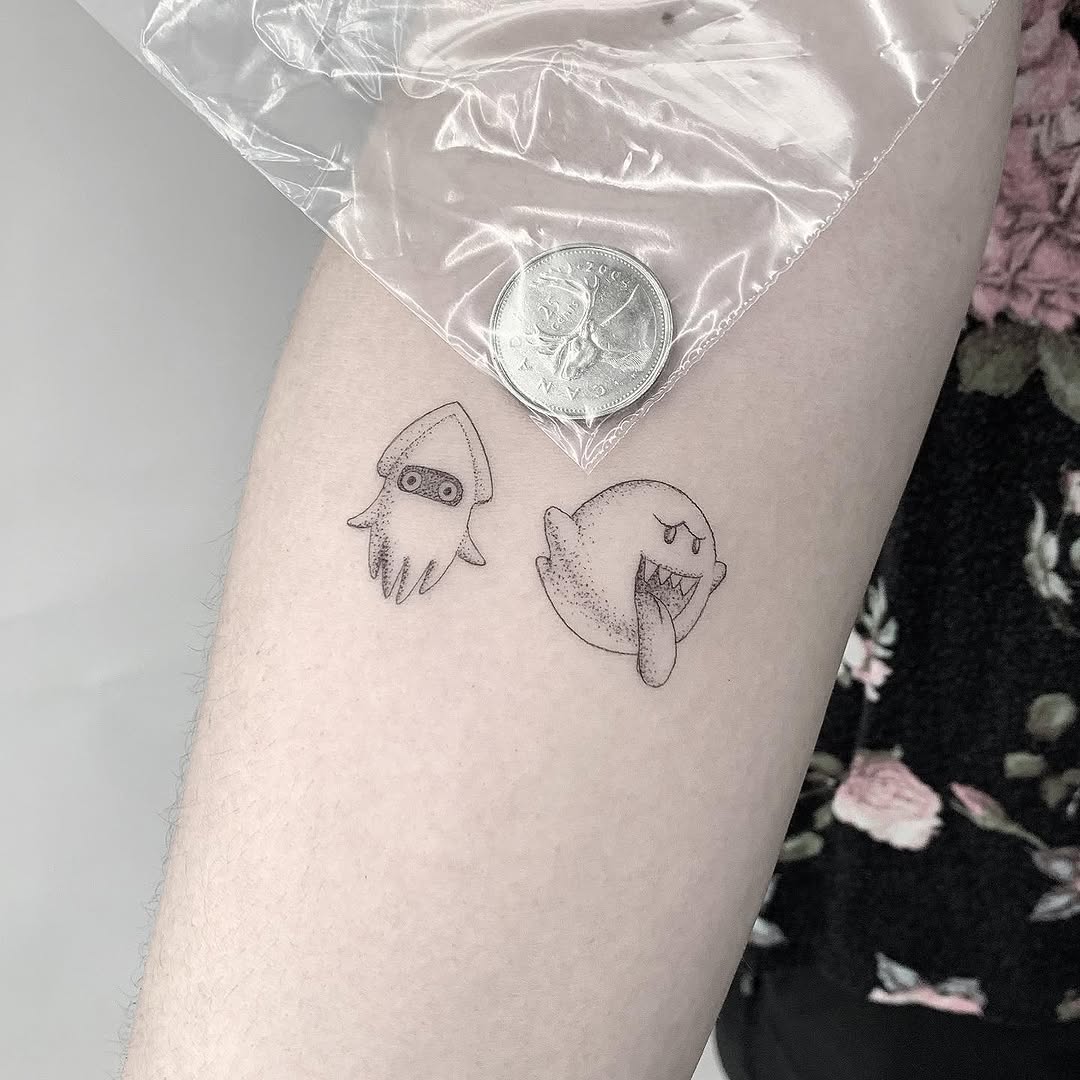 Two small line-drawn characters on forearm: a rocket-headed figure and a round character with tongue out.
