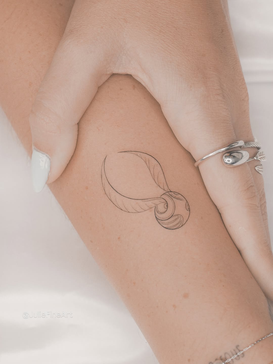 Minimalist line drawing of a sleeping face with flowing hair, rendered in hairline strokes on the upper arm.