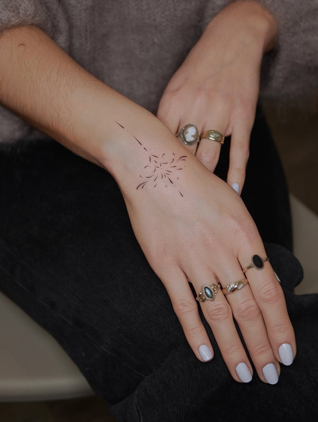 Delicate fine-line sun tattoo on inner forearm with minimal linework and airy composition.