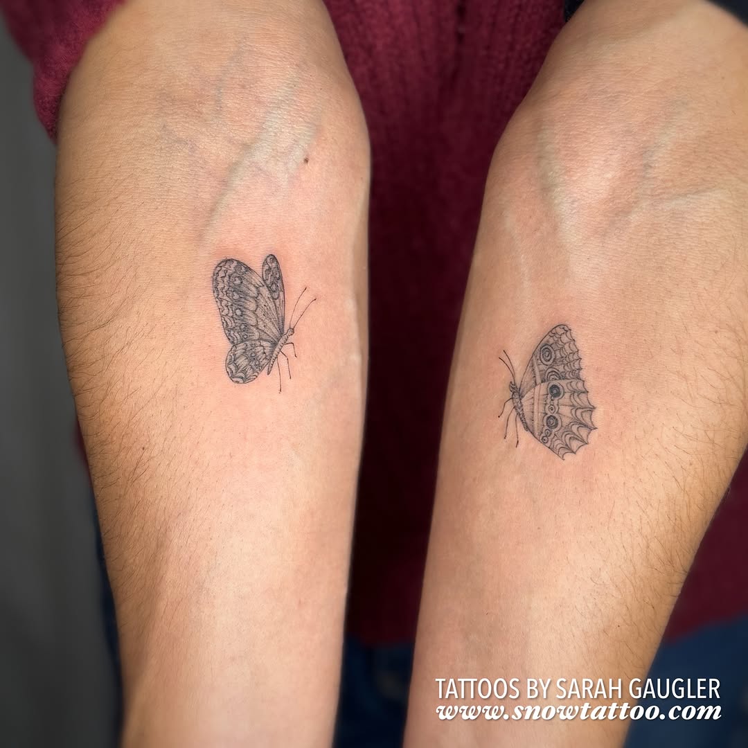 Two delicate butterflies with intricate wing detail tattooed on the calves in black ink.