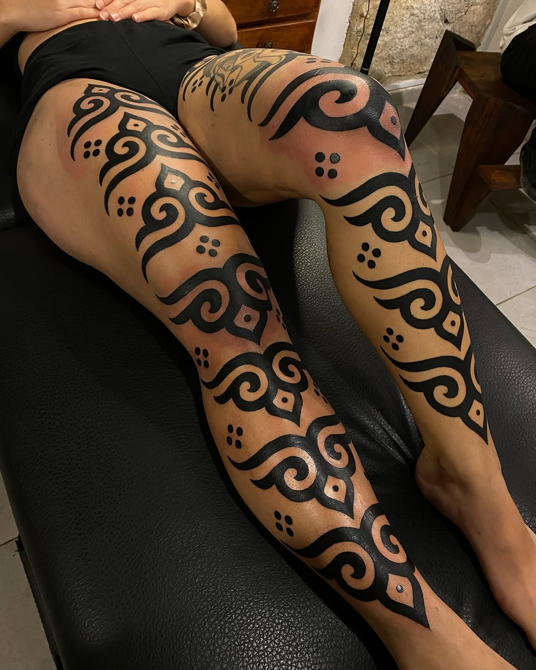 Symmetrical ornamental black linework with scrolling curves and dotwork accents covering both legs.