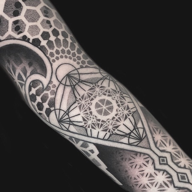 Geometric mandala and sacred geometry sleeve tattoo with intricate dotwork, linear patterns, and symmetrical ornamental designs on forearm.