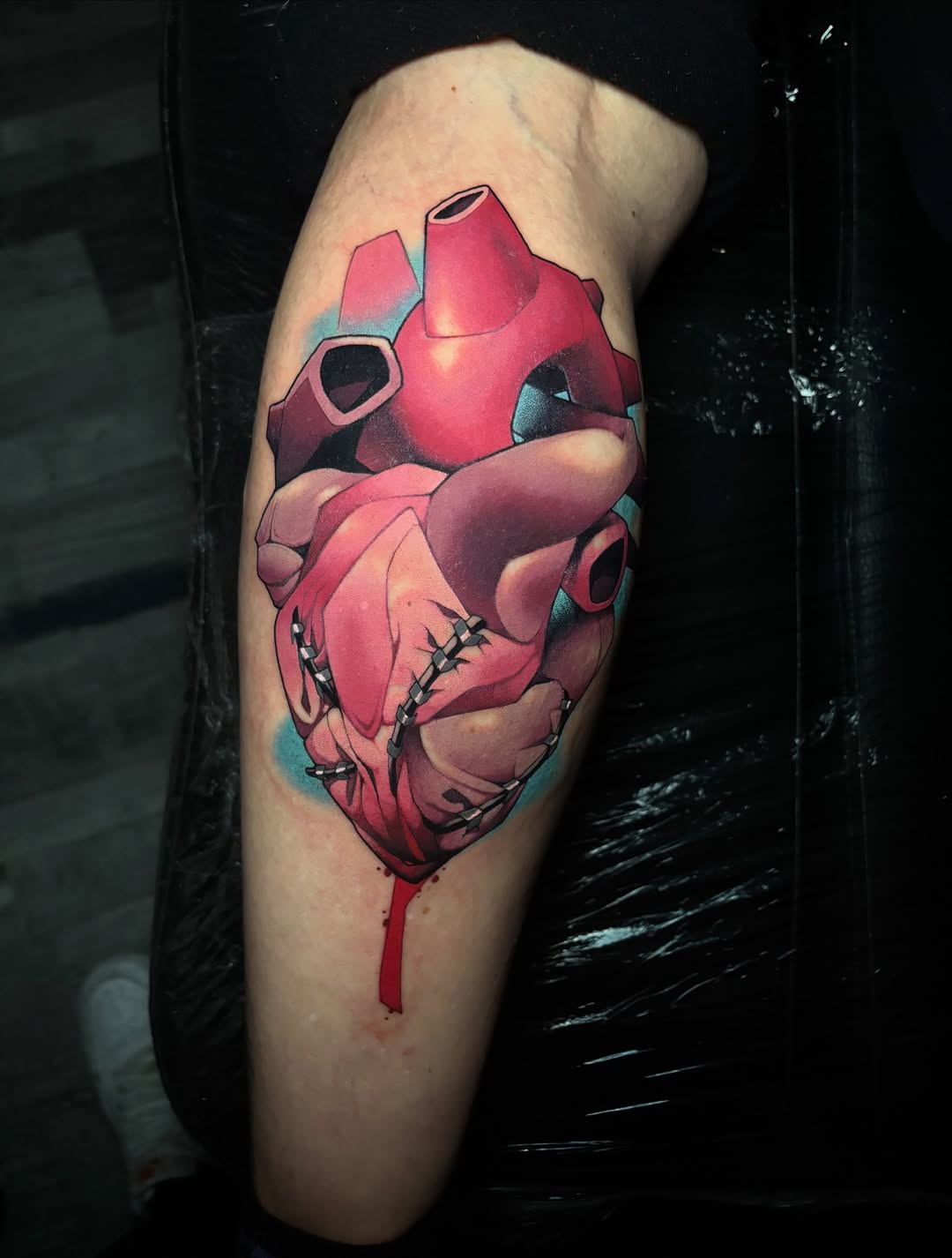 Stylized anatomical heart with robot/mechanical head hybrid, red and teal colors, on upper arm with dripping effect.