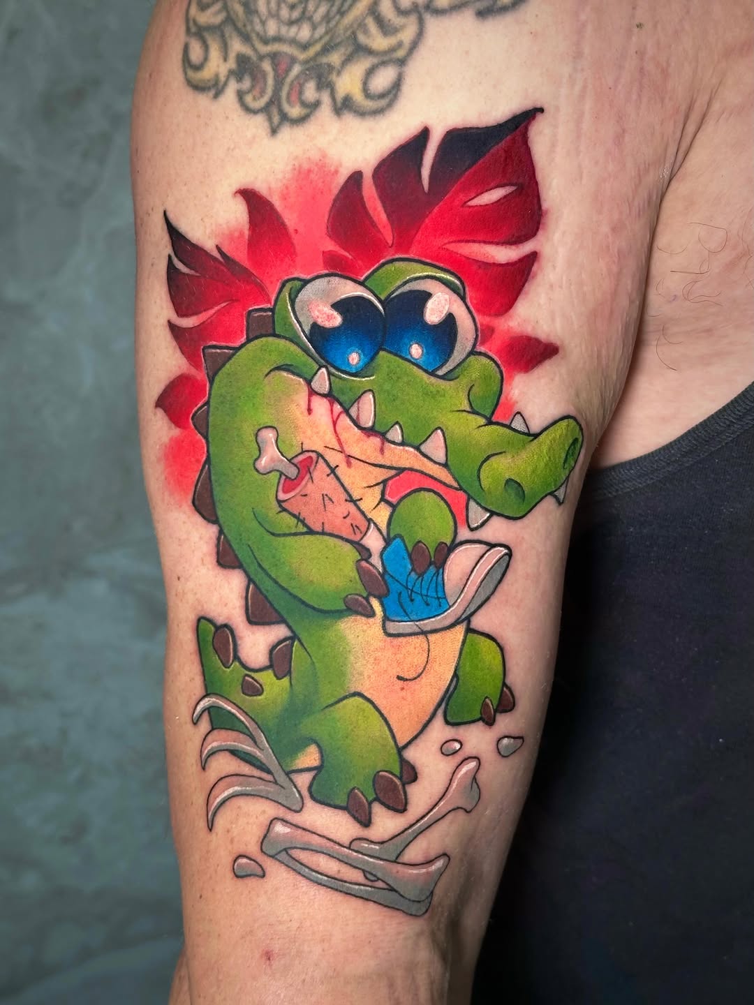 Green cartoon dinosaur with exaggerated features, large blue eyes, red spiky back, and open mouth expression on thigh.